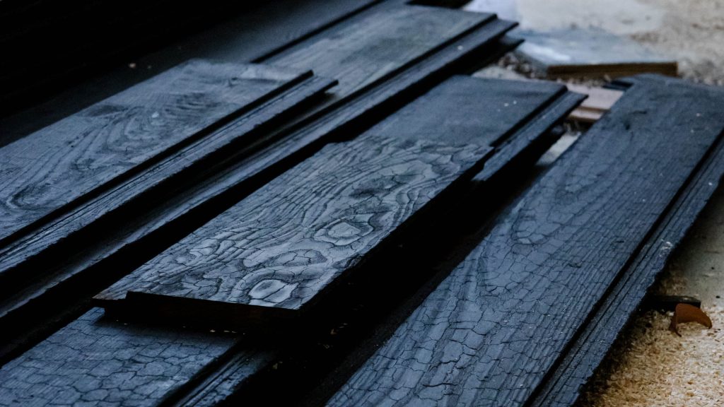 Close-up texture of charcoal Sujiban wood panel in a modern lobby